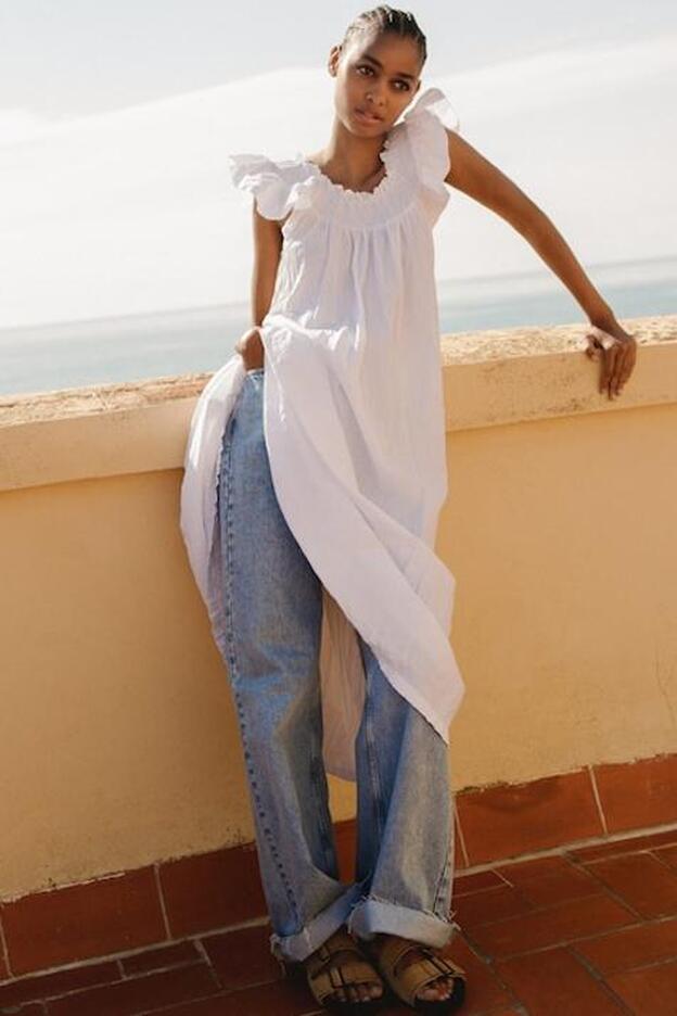 Vestido blanco midi con silueta romántica y suelta sobre vaqueros.